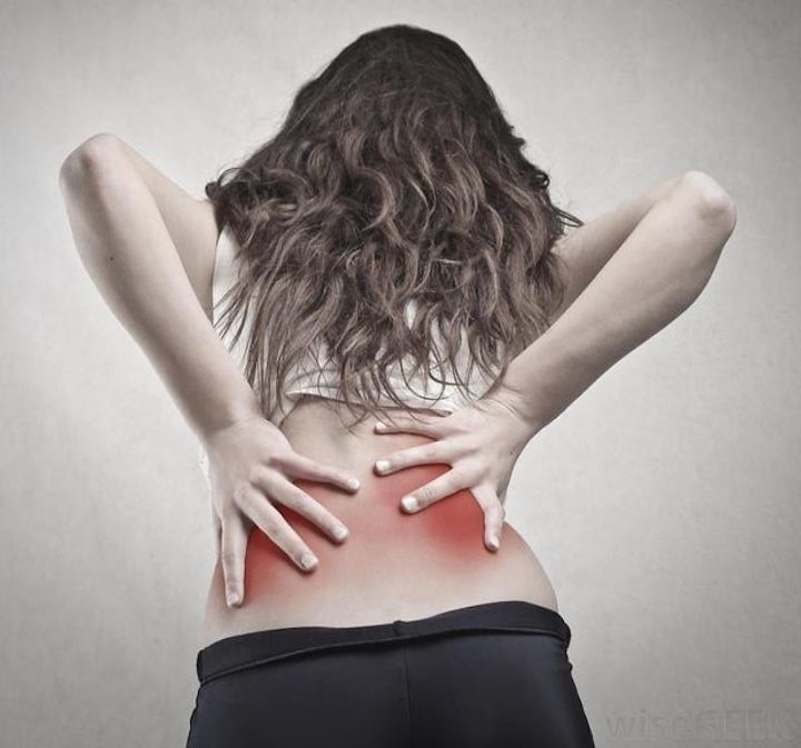 young woman with her back to the camera, in obvious pain, with red blotches on her lower back
