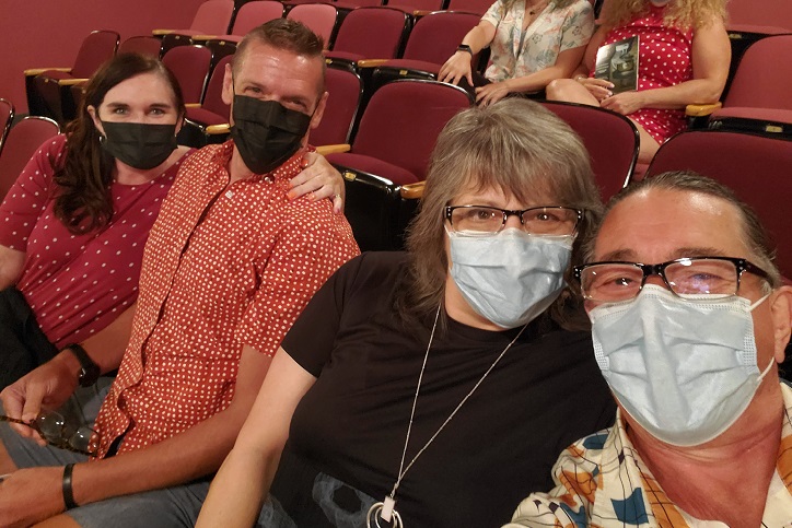 Left to right, Nora, Ken, me, and Derek, wearing masks and sitting in red theatre seats of Port Stanley Festival Theatre. 