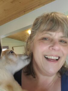 A close up of me in a selfie with a baby goat nibbling on my hair at the side of my head