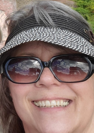 A close up of me smiling wearing a visor and big sunglasses