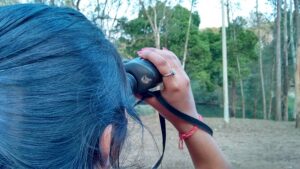 A woman looking at woods with binoculars. Photo by Aniket Suryavanshi via Flickr