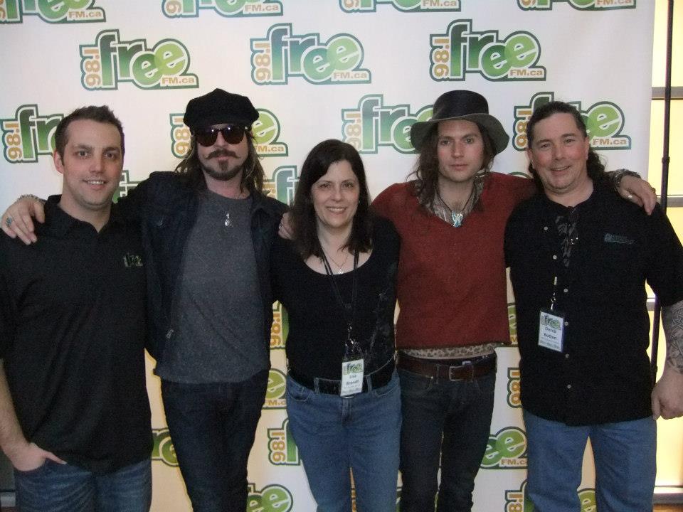 Blair, me and Derek with Scott and Jay of Rival Sons, posing in front of the Free-FM banner in 2013