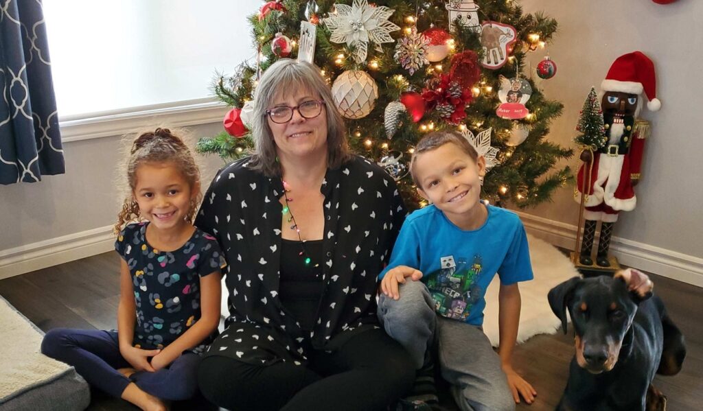 Me, 6 year old Vienna, 9 year old Ryker, and 6 month old Cario the Doberman, posing in front of a Christmas tree.