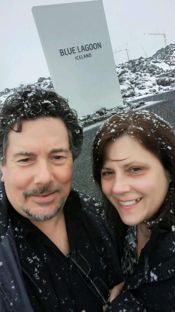 Derek and I in a selfie in front of the Blue Lagoon, Iceland sign, with my obvious tooth gap in a wide smile.