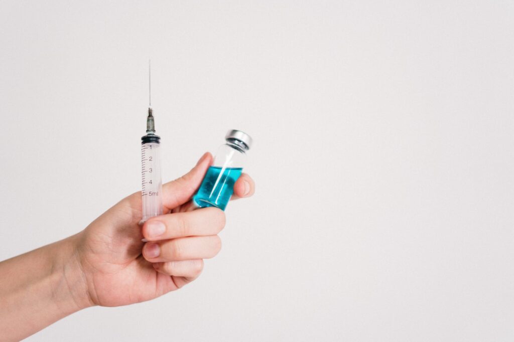 person holding syringe and vaccine bottle