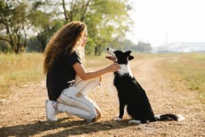 woman petting border collie on pathway