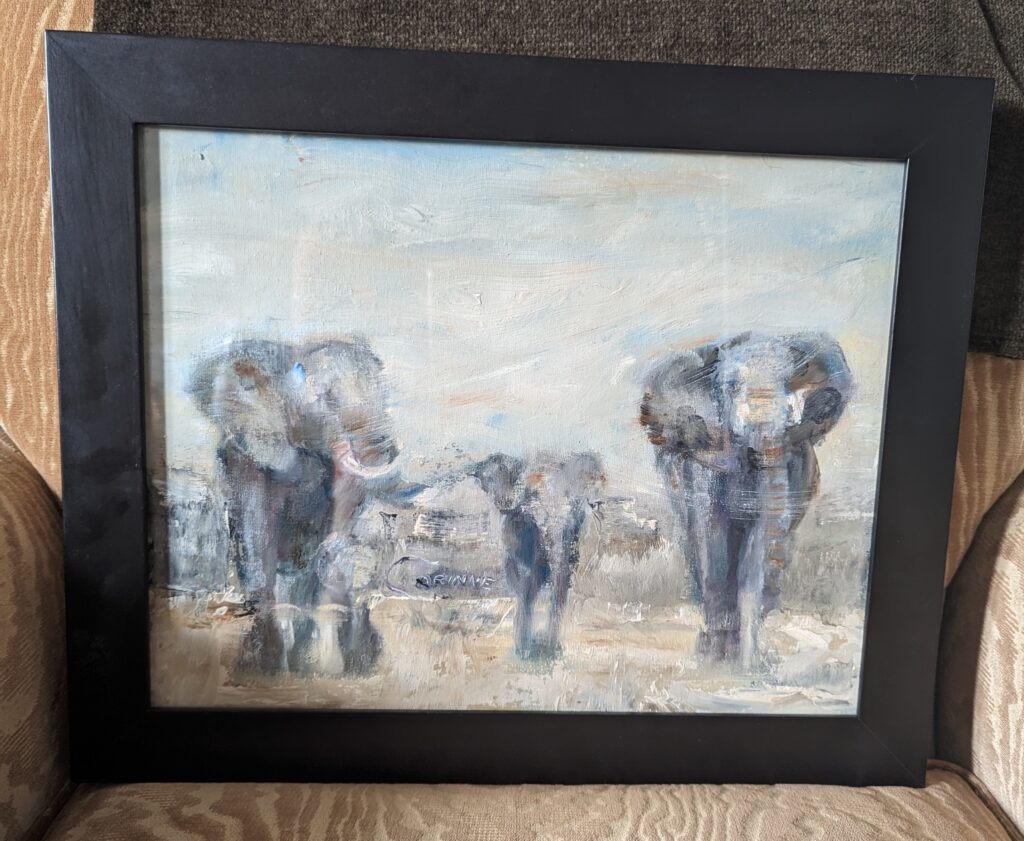 Painting of three grey elephants in a black frame. 