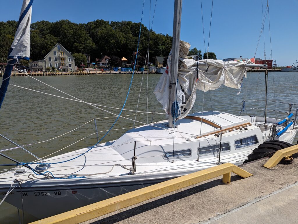 A white sailboat with its sail down and wrapped around the mast.