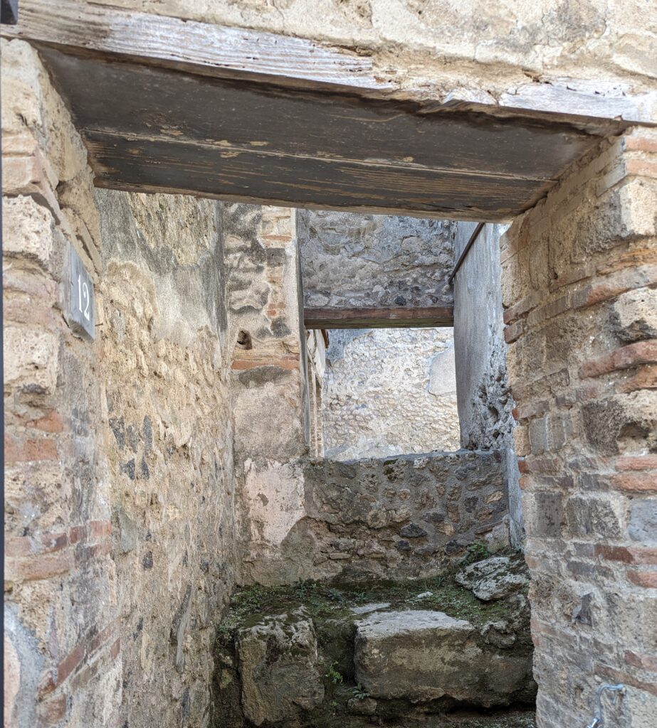 Stone walls surround a stone bed that presumably would have had leaves or something softer on it before a working woman brought a client in. 