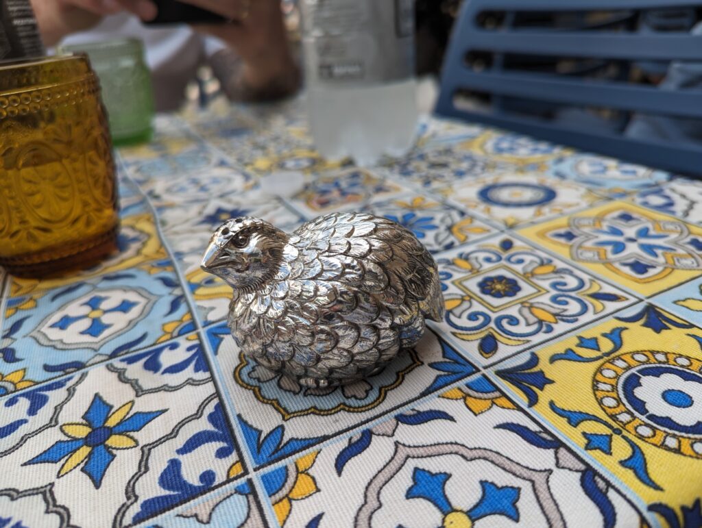 The little metal urn (actually, it's a salt shaker) holding what remain of Mom's ashes, on a colourful tablecloth at a restaurant on the island of Capri.