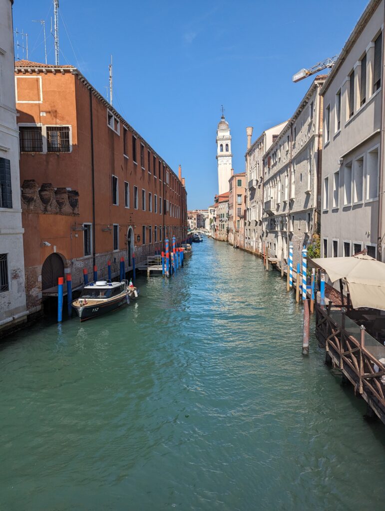 A curved canal in Venice between tall sets of beautiful old buildings. 