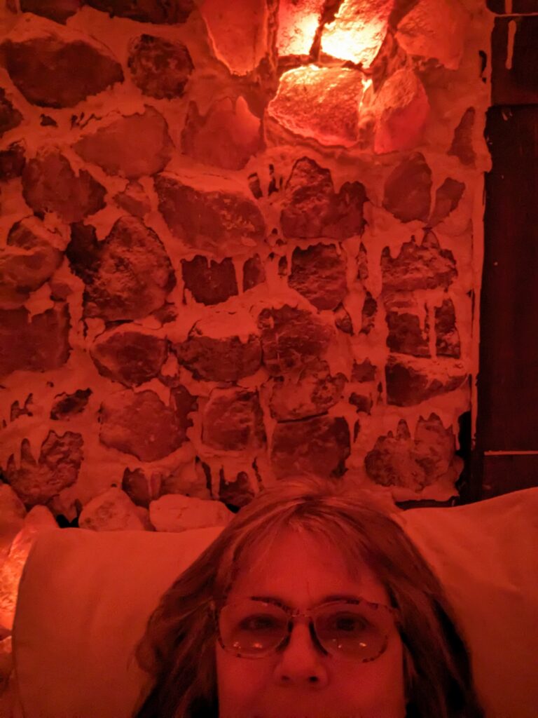 Me, lying back on a lounge chair in a reddish environment with rocks and salt on the walls, and dim lighting. 