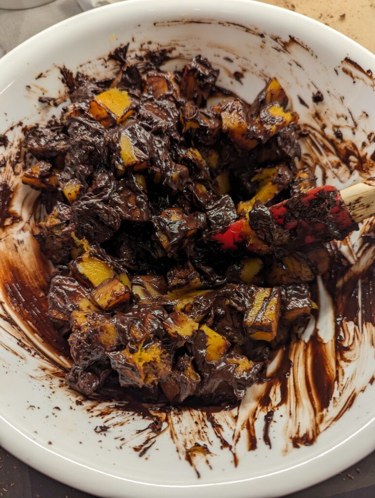 Chocolate melted over chunks of squash and a spatula in the middle. 