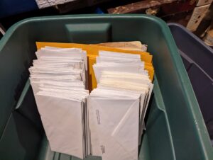 green plastic tote almost filled with envelopes stacked on end