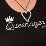 Black tee with the Queenagers image and a G and F pendant showing
