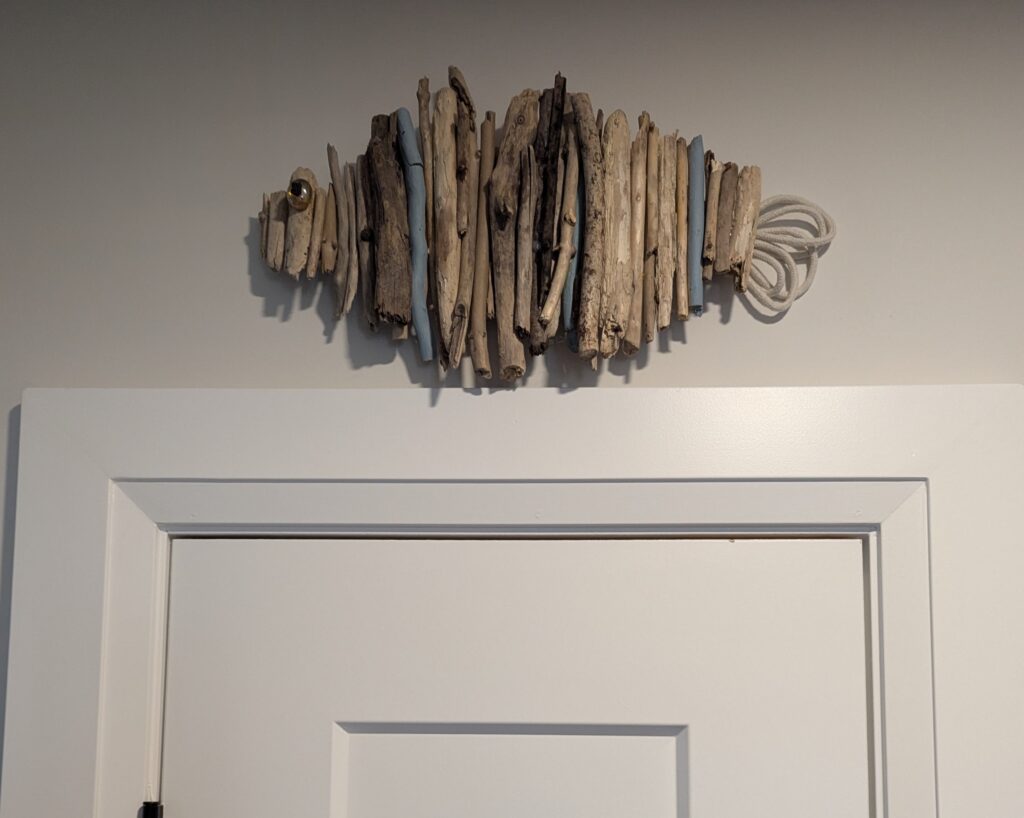 A fish made of twigs and small branches has a tail made from looped fishing rope and an eye from a piece of seaglass. 