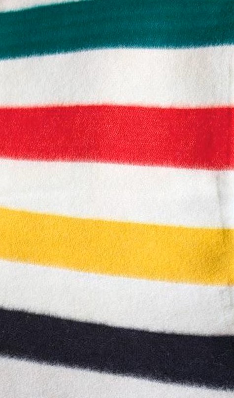 closeup of the colours in the HBC wool blanket. Stripes of green, red, yellow, and black.