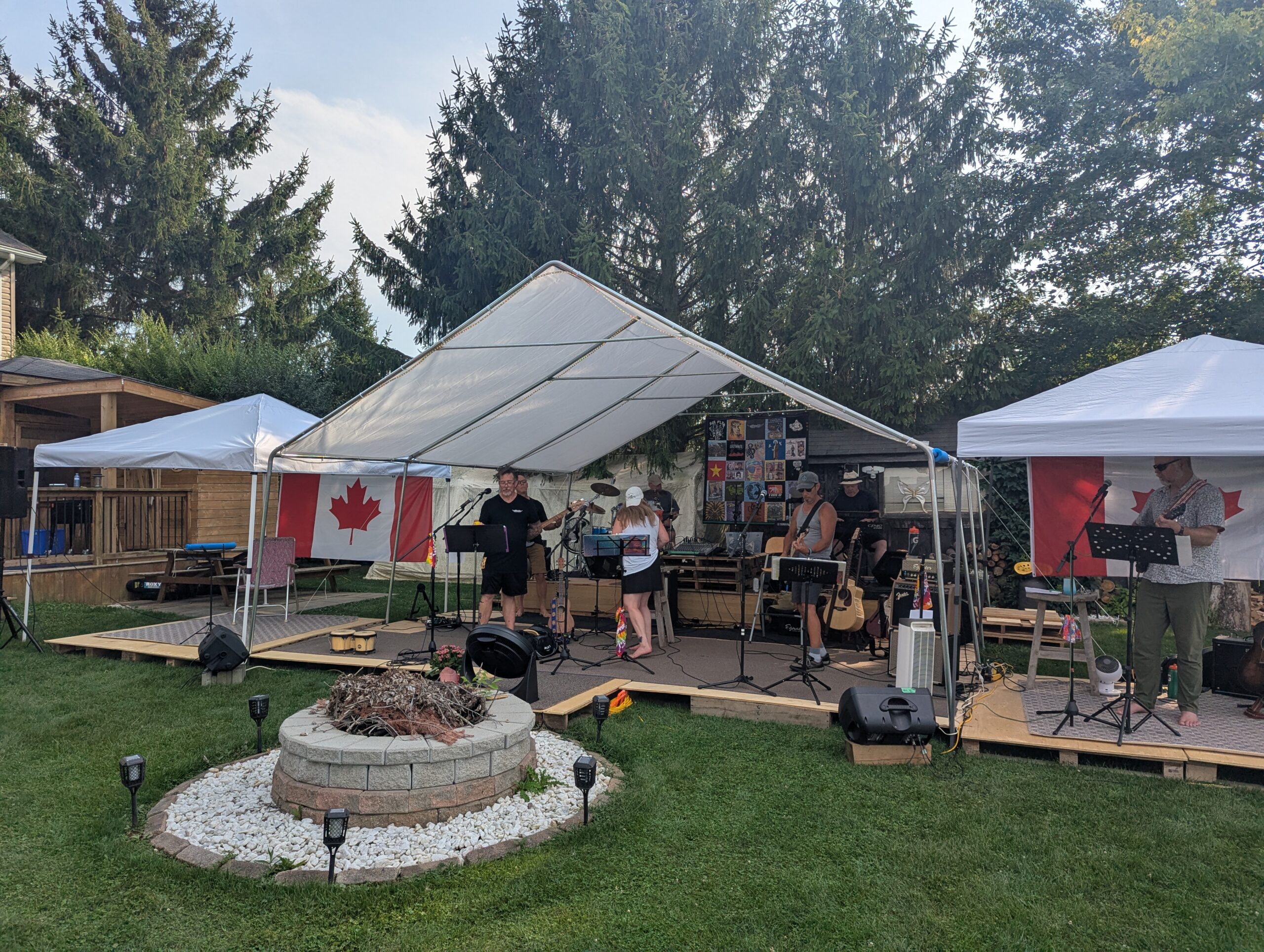 Full view of the long stage under three large tents with the band in the middle, and guitarist Neil at the far right.