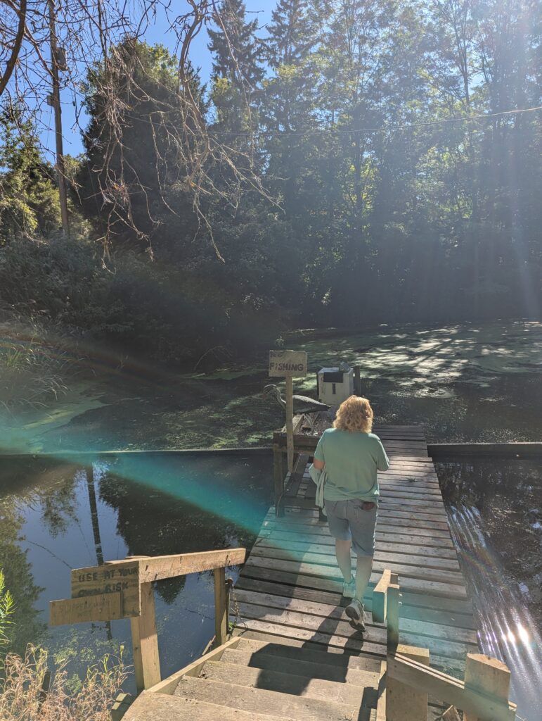 Blonde woman in denim shorts and hoodie leads me down a dock.