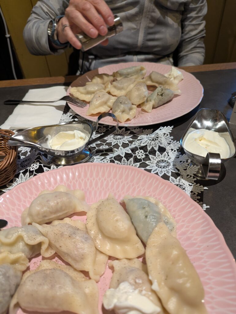Two plates of boiled perogies and you can see BA's hand adding pepper to hers