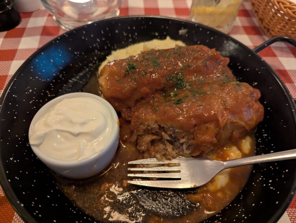 two large cabbage rolls with a side of sour cream