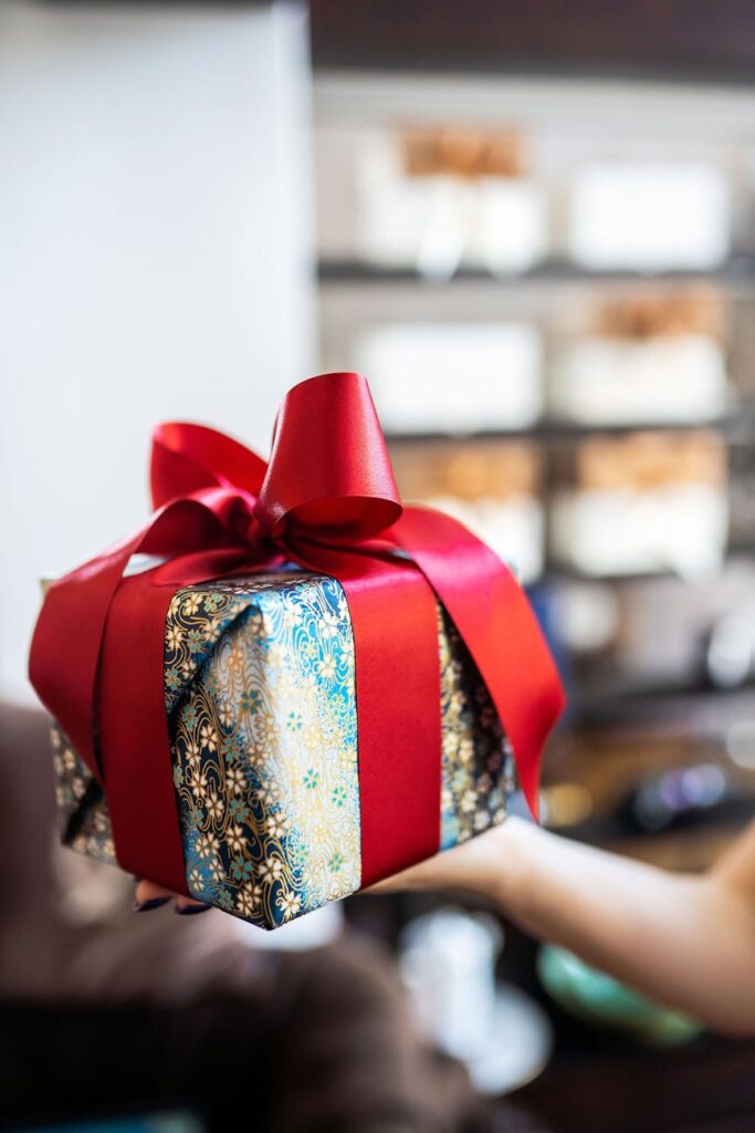 holding a gift box tied with a red ribbon