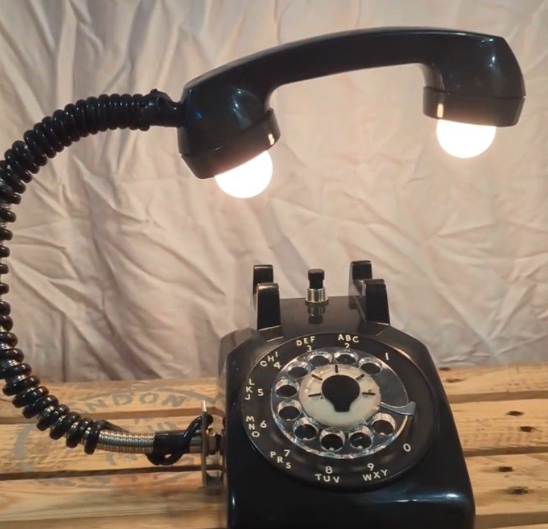 An old rotary phone whose receiver stays upright and has a bulb in both the talking and the listening ends