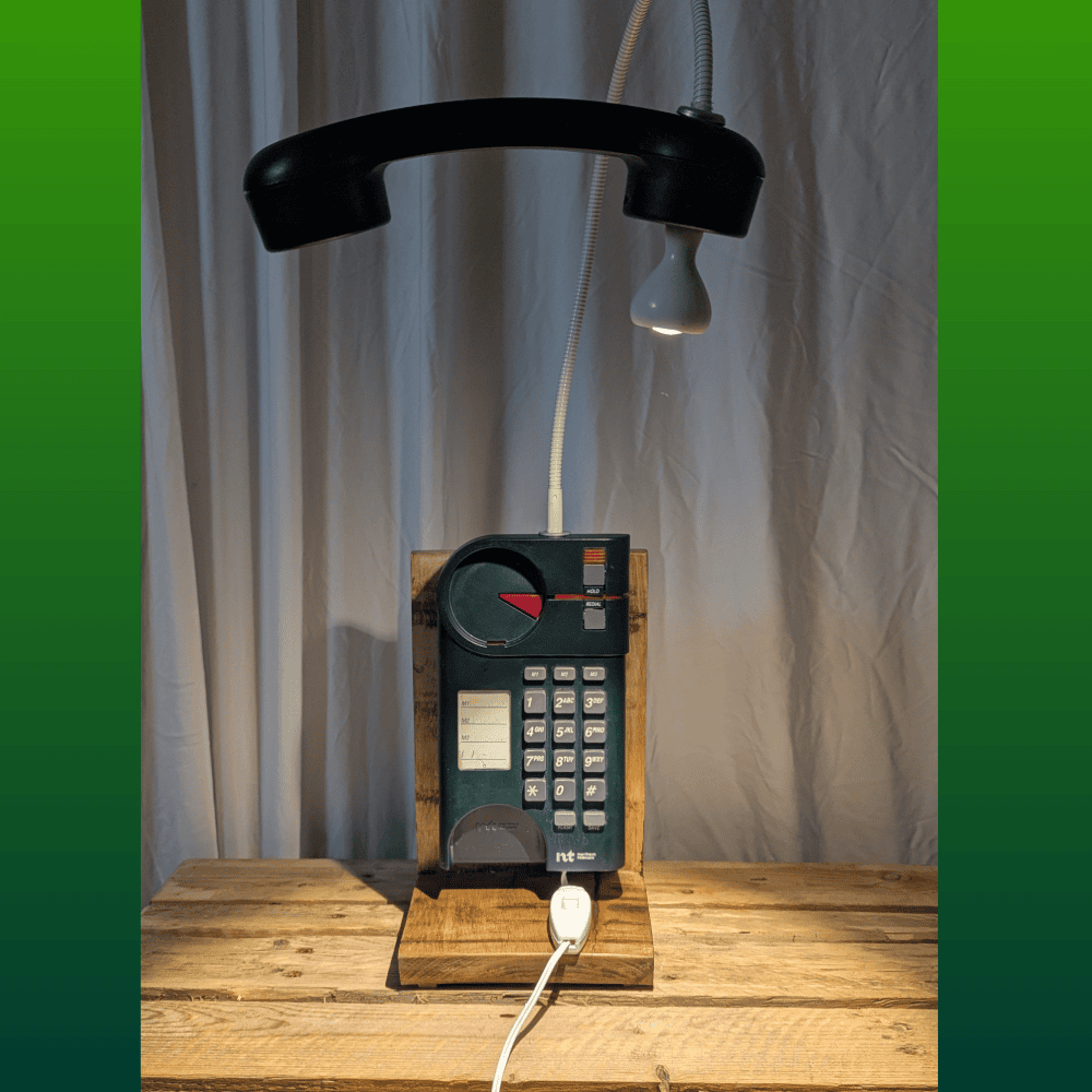 Green push-button phone with its receiver overhead, lit up.