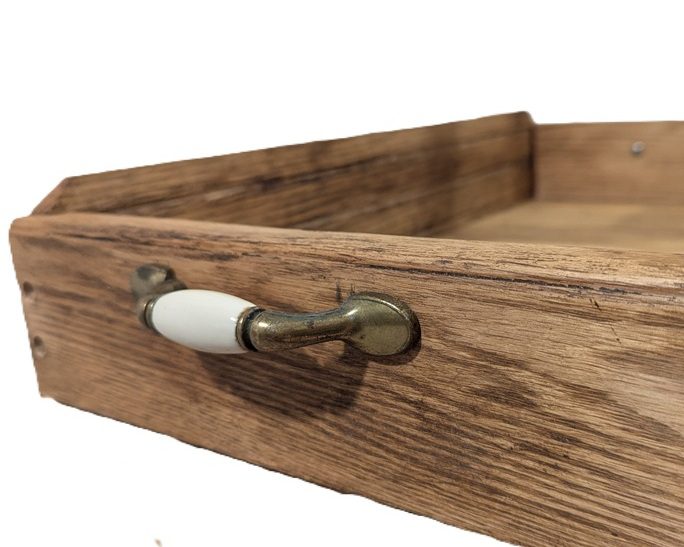 The corner of an oak tray shows the vintage handles