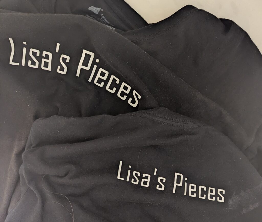 Our black Lisa's Pieces t-shirts on the floor, soaking wet and looking limp.
