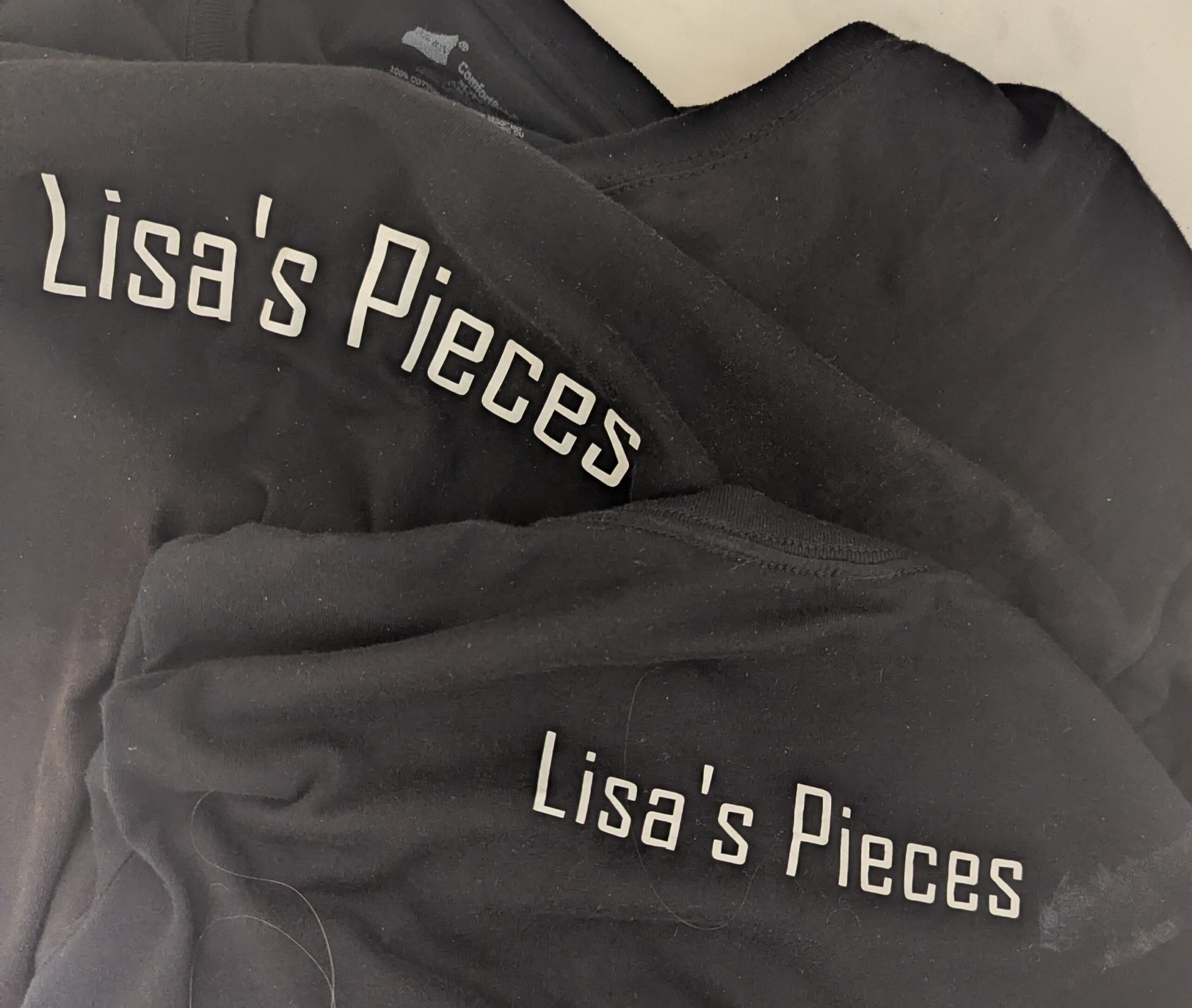 Our black Lisa's Pieces t-shirts on the floor, soaking wet and looking limp.